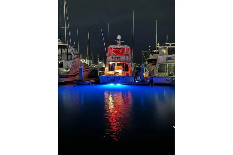  Yacht Photos Pics 1979 Bertram 46.6 Sport Fisher with vibrant blue and red lights at night.