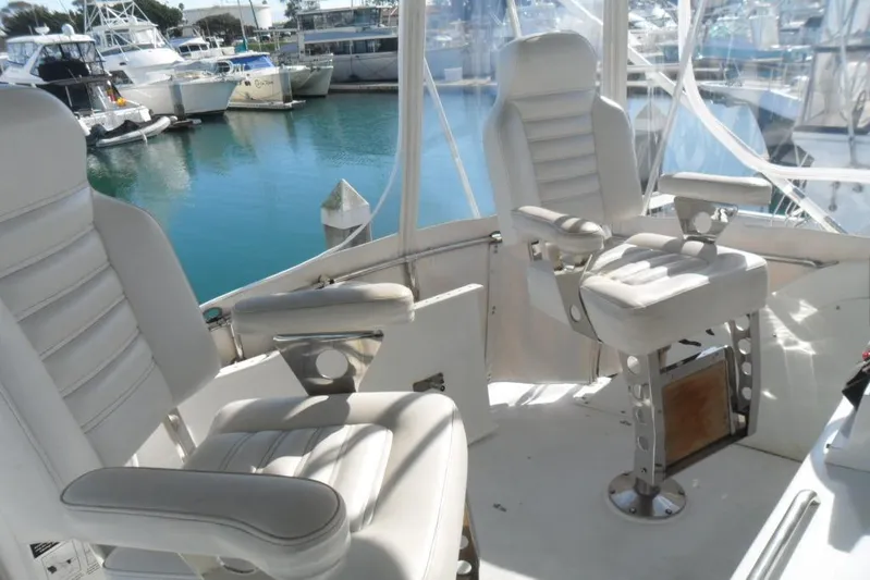  Yacht Photos Pics 1979 Bertram 46.6 Sport Fisher cockpit with white captain chairs in marina setting.