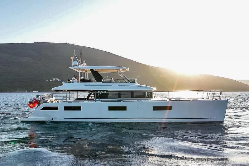  Yacht Photos Pics 2020 Lagoon 630 MY yacht cruising at sunset near a mountainous coastline.