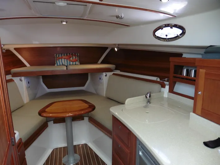  Yacht Photos Pics 2016 Back Cove 30 interior with cozy seating, wooden table, and compact kitchenette.