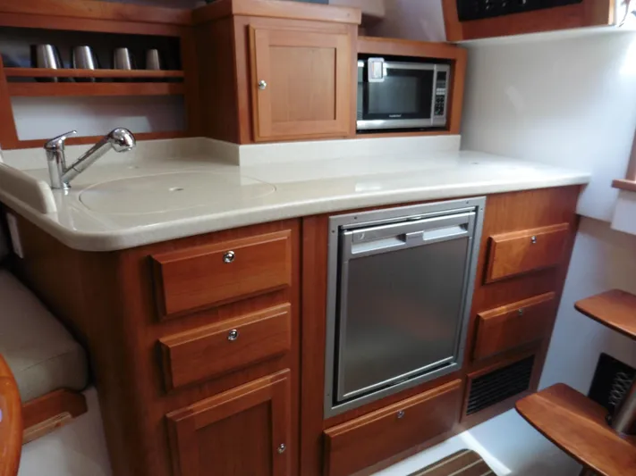  Yacht Photos Pics 2016 Back Cove 30 yacht kitchen with wooden cabinetry, microwave, and compact fridge.