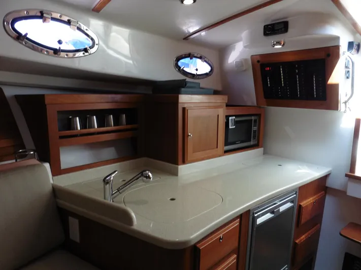  Yacht Photos Pics 2016 Back Cove 30 yacht interior with kitchenette, featuring sink, microwave, and wooden cabinetry.