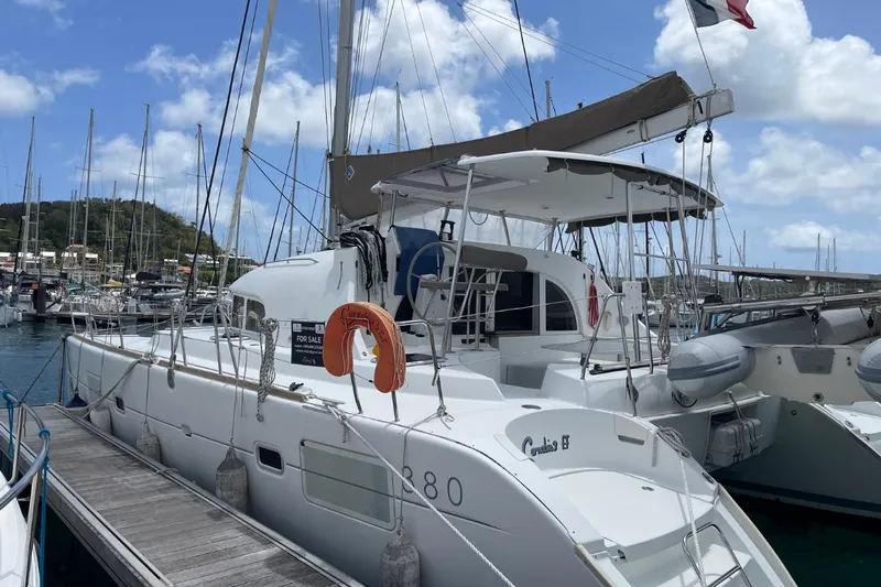 Carnabie Yacht Photos Pics 2014 Lagoon 380 S2 catamaran docked at marina, clear sky, for sale sign visible.