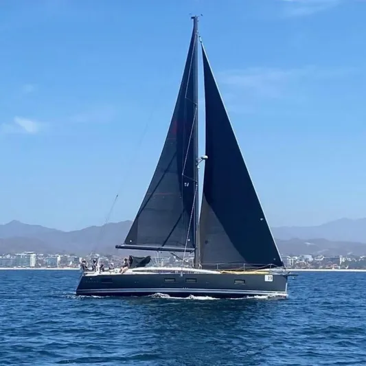 Edwina Yacht Photos Pics 2018 Jeanneau 54 sailboat cruising on open water with mountains in the background.