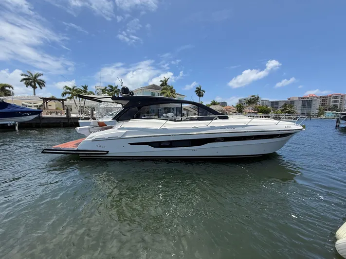  Yacht Photos Pics 2023 Rio Yachts SPORT COUPE on water, with palm trees and buildings in background.