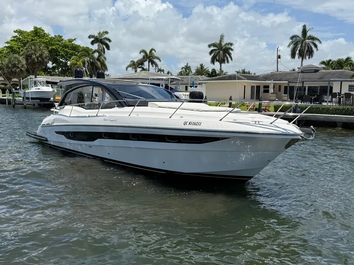  Yacht Photos Pics 2023 Rio Yachts SPORT COUPE on water, surrounded by palm trees and waterfront homes.
