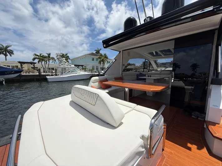  Yacht Photos Pics 2023 Rio Yachts SPORT COUPE with luxurious seating and dining area, docked by palm trees.