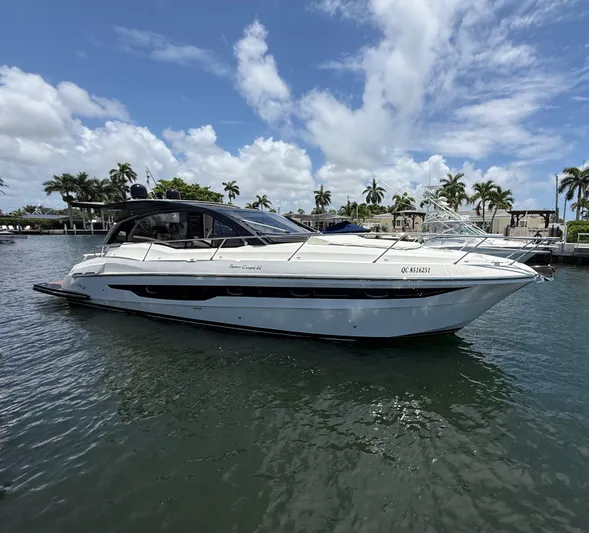  Yacht Photos Pics 2023 Rio Yachts SPORT COUPE on water, sleek design, sunny day, palm trees in background.