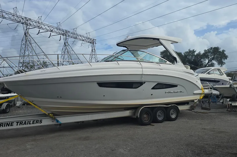  Yacht Photos Pics 2019 Regal 33 OBX boat on trailer, parked outdoors under cloudy sky.