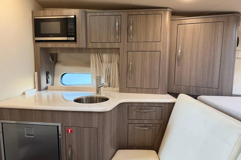  Yacht Photos Pics 2019 Regal 33 OBX boat interior kitchen with microwave, sink, and wooden cabinets.