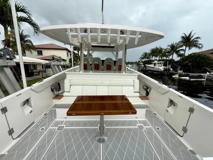 Yacht Photos Pics 2021 Regal 38 SAV boat with spacious deck, seating, and table, docked near waterfront homes.