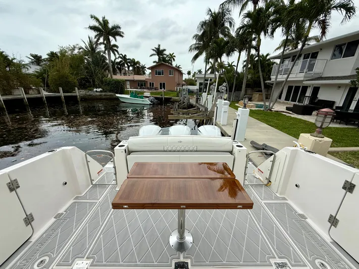  Yacht Photos Pics 2021 Regal 38 SAV boat docked, featuring a sleek deck and wooden table, surrounded by palm trees.