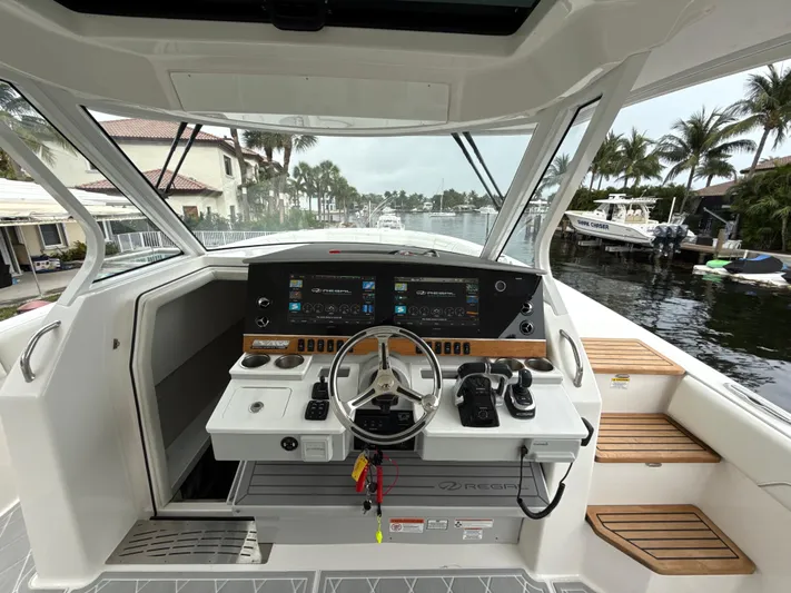  Yacht Photos Pics 2021 Regal 38 SAV boat helm with modern controls, docked near palm trees.