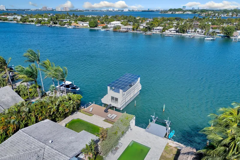  Yacht Photos Pics 2024 ARKUP 50 Liveable Yacht on serene waterfront, surrounded by lush greenery and modern homes.