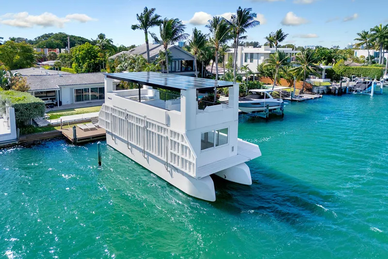  Yacht Photos Pics 2024 ARKUP 50 Liveable Yacht on turquoise water near luxury waterfront homes.