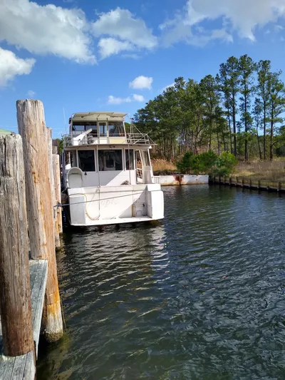 Elizabeth Yacht Photos Pics 1989 DeFever 57 POC Motor Yacht docked by wooden pier, surrounded by trees and blue sky.