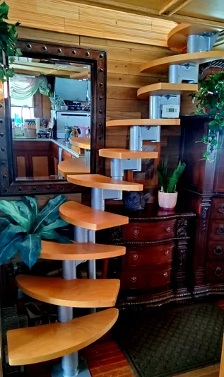 Elizabeth Yacht Photos Pics Spiral staircase in 1989 DeFever 57 POC Motor Yacht interior with wooden steps and decorative plants.