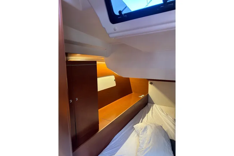  Yacht Photos Pics Interior cabin of 2019 Beneteau Oceanis 51.1 yacht, featuring cozy bedding and wooden cabinetry.