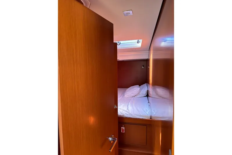  Yacht Photos Pics Cozy cabin interior of 2019 Beneteau Oceanis 51.1 yacht with wooden finish and bedding.