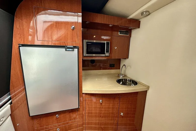  Yacht Photos Pics 2011 Regal 38 Express yacht interior with kitchenette, featuring wood cabinetry, sink, and microwave.