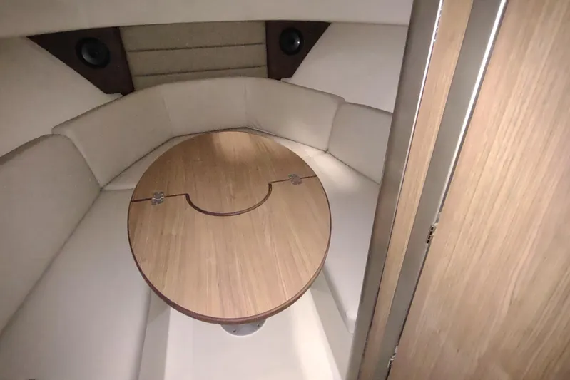 Yacht Photos Pics 2015 Boston Whaler 285 Conquest cabin interior with round wooden table and cushioned seating.