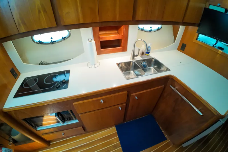 Sun Baked Yacht Photos Pics 1999 Tiara Yachts 3500 Express galley with stove, sink, and wooden cabinetry.