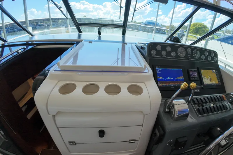 Sun Baked Yacht Photos Pics 1999 Tiara Yachts 3500 Express helm with navigation screens and controls, docked under a sunny sky.