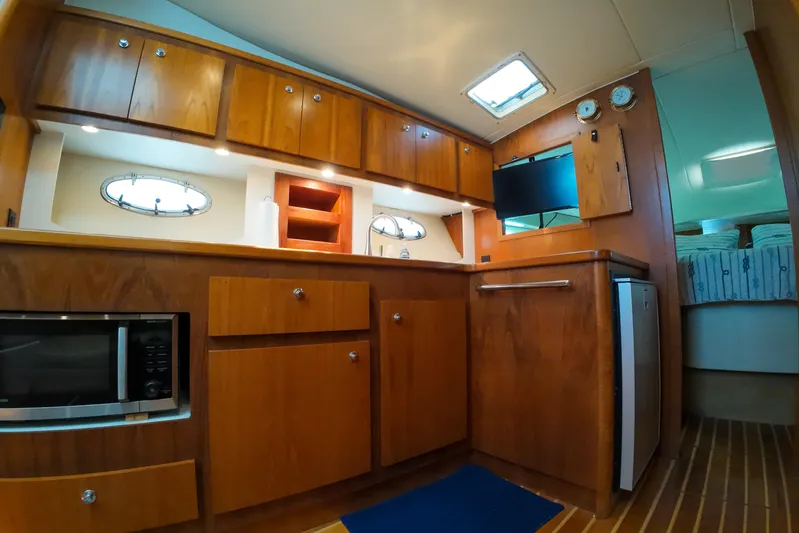 Sun Baked Yacht Photos Pics 1999 Tiara Yachts 3500 Express interior with wooden cabinetry, microwave, and compact fridge.