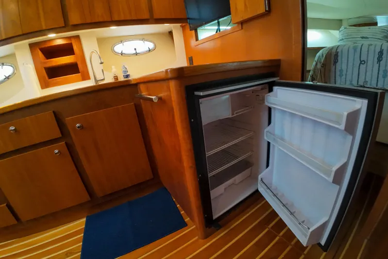 Sun Baked Yacht Photos Pics 1999 Tiara Yachts 3500 Express interior with open fridge and wooden cabinetry.