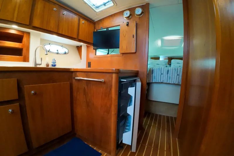 Sun Baked Yacht Photos Pics 1999 Tiara Yachts 3500 Express interior with wood cabinetry and compact kitchen area.