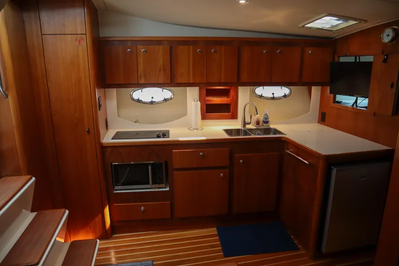 Sun Baked Yacht Photos Pics 1999 Tiara Yachts 3500 Express interior kitchen with wood cabinetry and modern appliances.