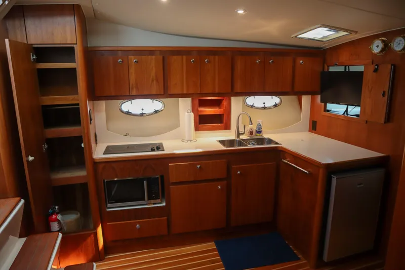 Sun Baked Yacht Photos Pics Interior of 1999 Tiara Yachts 3500 Express, featuring a well-equipped kitchen with wooden cabinetry.