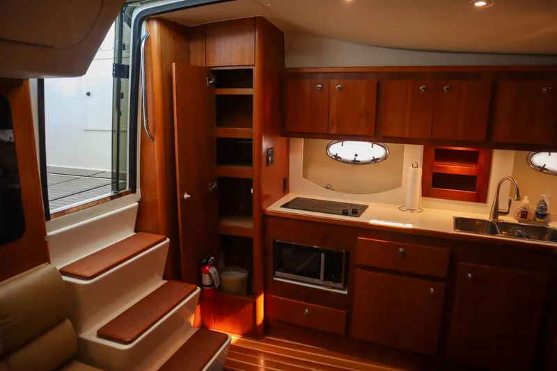 Sun Baked Yacht Photos Pics 1999 Tiara Yachts 3500 Express interior with wooden cabinetry and modern kitchen amenities.