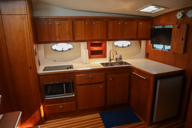 Sun Baked Yacht Photos Pics 1999 Tiara Yachts 3500 Express kitchen with wood cabinetry, sink, stove, and microwave.