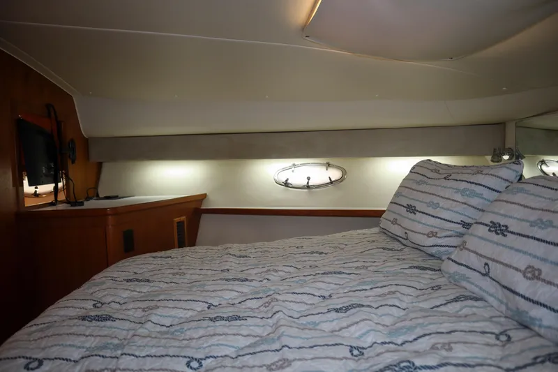 Sun Baked Yacht Photos Pics 1999 Tiara Yachts 3500 Express cabin interior with bed, porthole, and TV.