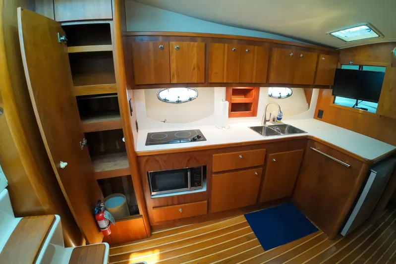 Sun Baked Yacht Photos Pics 1999 Tiara Yachts 3500 Express galley with wooden cabinets, stove, sink, and microwave.