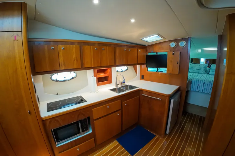 Sun Baked Yacht Photos Pics 1999 Tiara Yachts 3500 Express interior kitchen with wooden cabinets and modern appliances.
