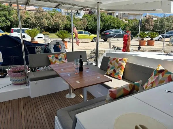 Angels Share Yacht Photos Pics Spacious deck of 2015 Lagoon 450 F catamaran with colorful cushions and wooden table.