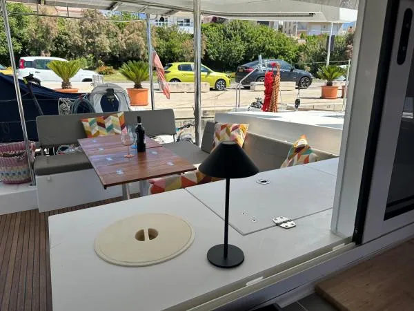 Angels Share Yacht Photos Pics Outdoor seating area on 2015 Lagoon 450 F yacht with table, lamp, and colorful cushions.