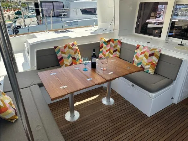 Angels Share Yacht Photos Pics Outdoor seating area on 2015 Lagoon 450 F yacht with colorful cushions and wooden table.