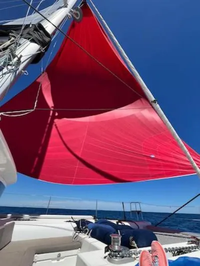 Angels Share Yacht Photos Pics Red sail on a 2015 Lagoon 450 F catamaran against a clear blue sky.