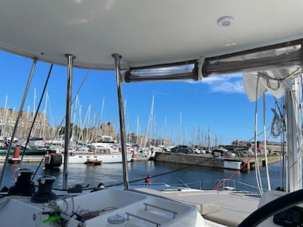 Angels Share Yacht Photos Pics Lagoon 450 F catamaran in a marina, surrounded by sailboats under a clear blue sky.