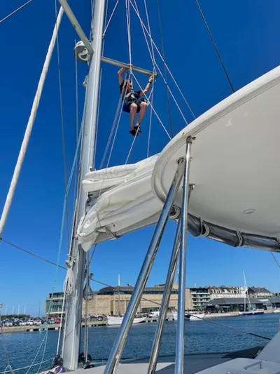 Angels Share Yacht Photos Pics Person climbing mast on 2015 Lagoon 450 F catamaran in sunny marina.