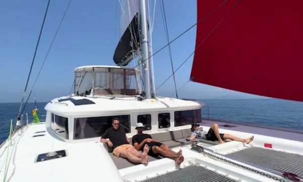 Angels Share Yacht Photos Pics People relaxing on a 2015 Lagoon 450 F catamaran with red sail, at sea.