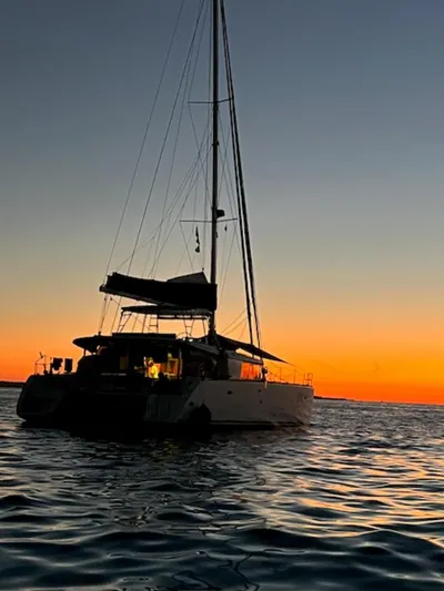Angels Share Yacht Photos Pics Lagoon 450 F catamaran silhouetted against a vibrant sunset over calm waters.