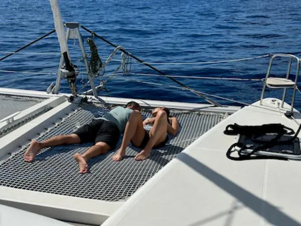 Angels Share Yacht Photos Pics Couple relaxing on Lagoon 450 F catamaran netting, 2015 model, with ocean backdrop.