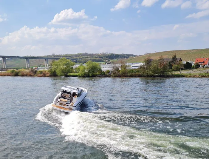 Inventory Clearance Yacht Photos Pics 2023 Bavaria SR41 COUPE cruising on a scenic river with a bridge in the background.
