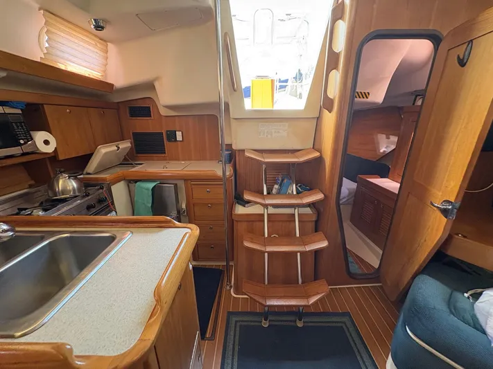 Ventosa Yacht Photos Pics Interior of a 2006 Catalina 350 sailboat, featuring a compact kitchen and wooden cabinetry.