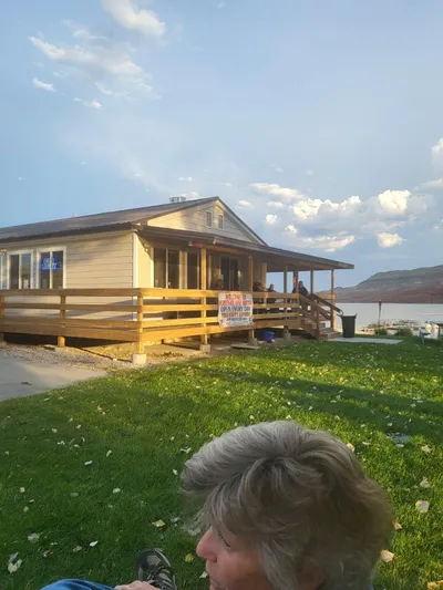 Mv Belle Yacht Photos Pics Tour boat business building with wooden deck, green lawn, and lake view.