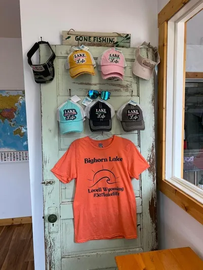 Mv Belle Yacht Photos Pics Lake Life hats and Bighorn Lake t-shirt on display in a rustic shop.